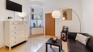 A living room with a sofa, a coffee table, a TV, a lamp, and a bookshelf.