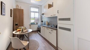 A compact kitchen with a dining area, a window, and a pendant light.