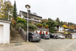 Un immeuble résidentiel avec un escalier menant à un garage, des voitures garées et un lampadaire.