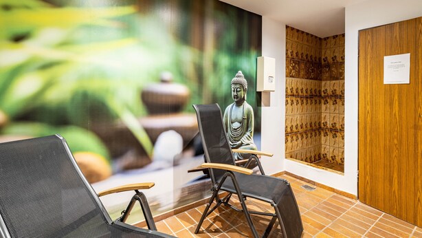 Ein Zimmer mit Buddha-Statue, einer Holzpaneelwand und einem gefliesten Boden.