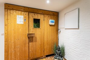 Une porte en bois avec une fenêtre, une petite statue de Bouddha et un mur blanc à la texture particulière.
