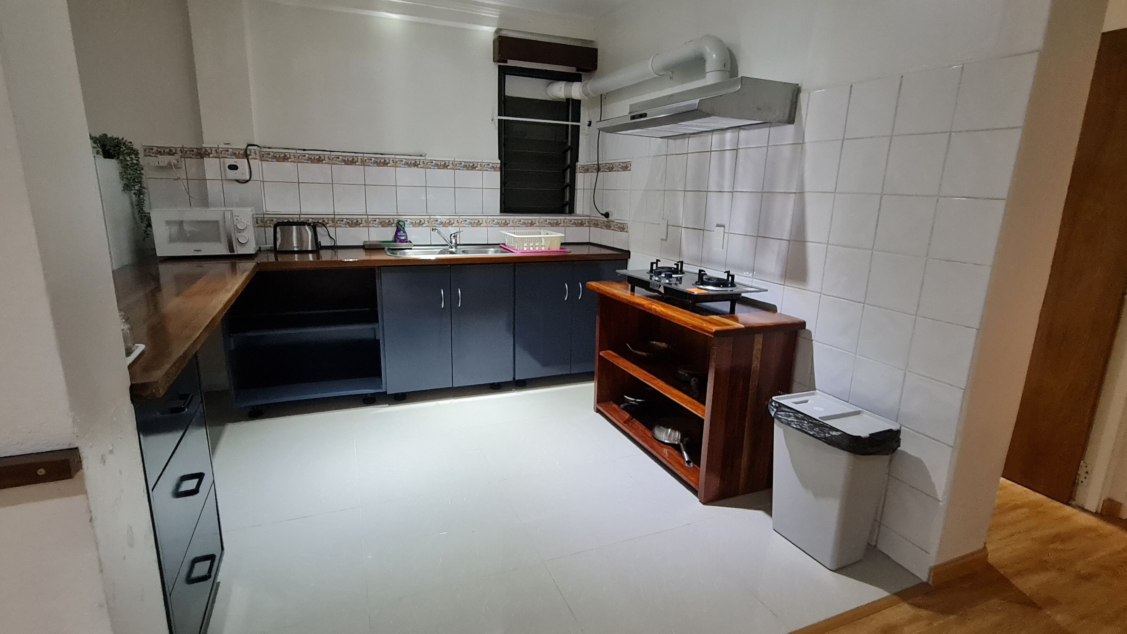 Uma cozinha compacta com azulejos brancos, fogão embutido e uma pia pequena.