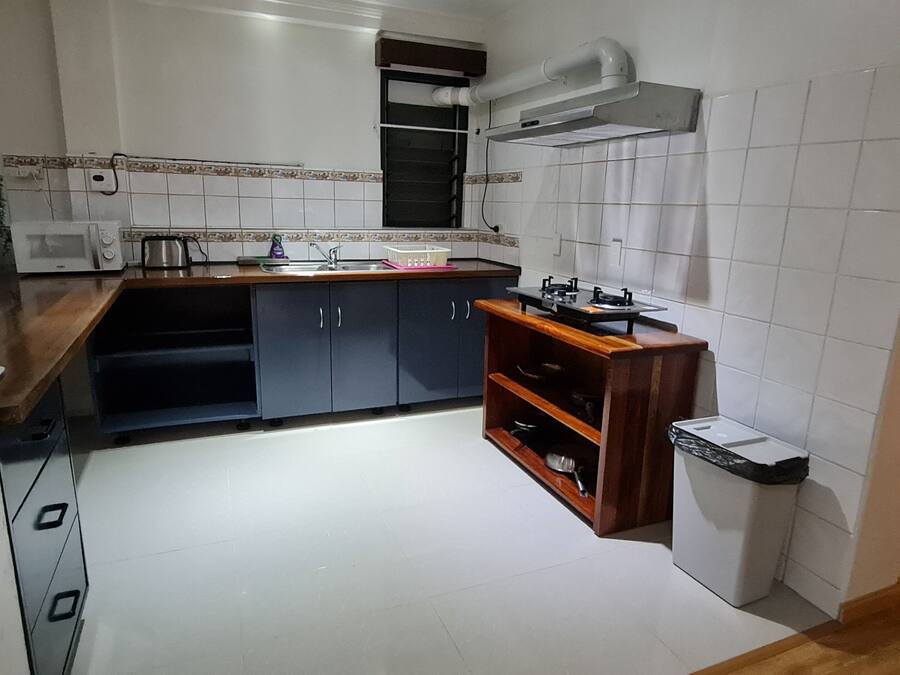Uma cozinha compacta com azulejos brancos, fogão embutido e uma pia pequena.