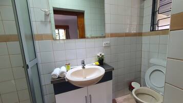 Une salle de bain avec un lavabo, un miroir, des toilettes et une petite fenêtre.