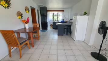 Una cocina moderna con comedor, que incluye una mesa y sillas de madera, un refrigerador y un ventilador.