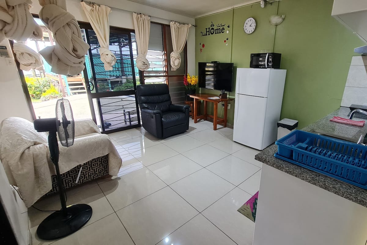 A compact kitchen with a refrigerator, a sink, and a dining area with a chair and table.