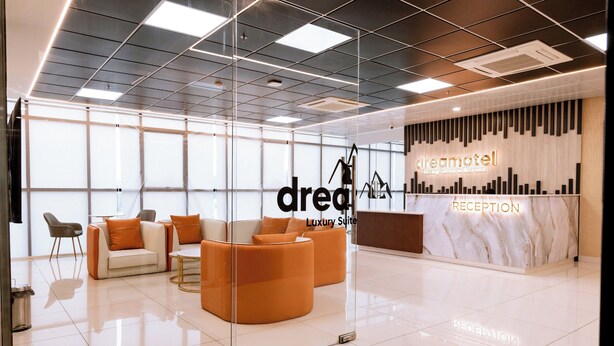 A modern reception area with a marble counter, glass partitions, and orange seating. - Dreamotel Luxury Suites and Rooms (Palakkad)