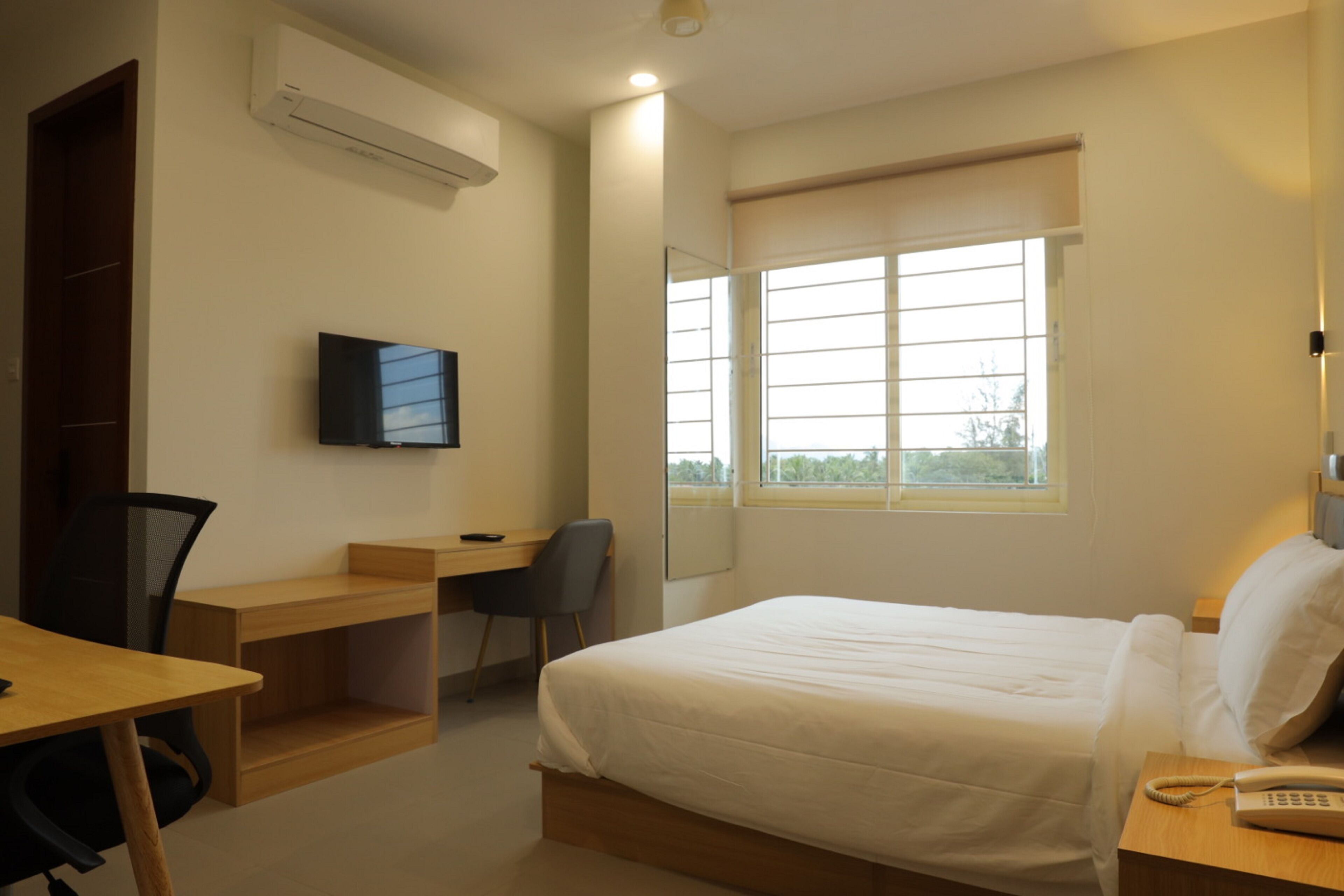 Un dormitorio con cama, escritorio, silla y televisor.