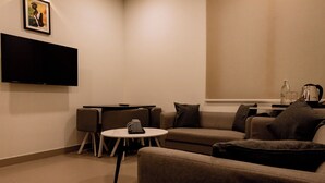 A modern living room with a flat-screen TV, a round coffee table, and a sofa set. - Dreamotel Luxury Suites and Rooms (Palakkad)