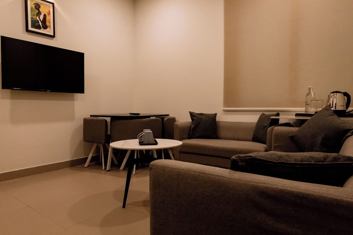 Un salon moderne avec un téléviseur à écran plat, une table basse ronde et un ensemble de canapés.