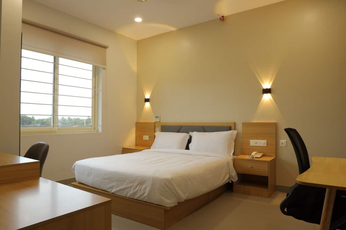 Une chambre d’hôtel avec un lit, des tables de chevet, un bureau et une chaise.