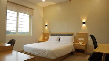 Una habitación de hotel con cama, mesitas de noche, un escritorio y una silla.