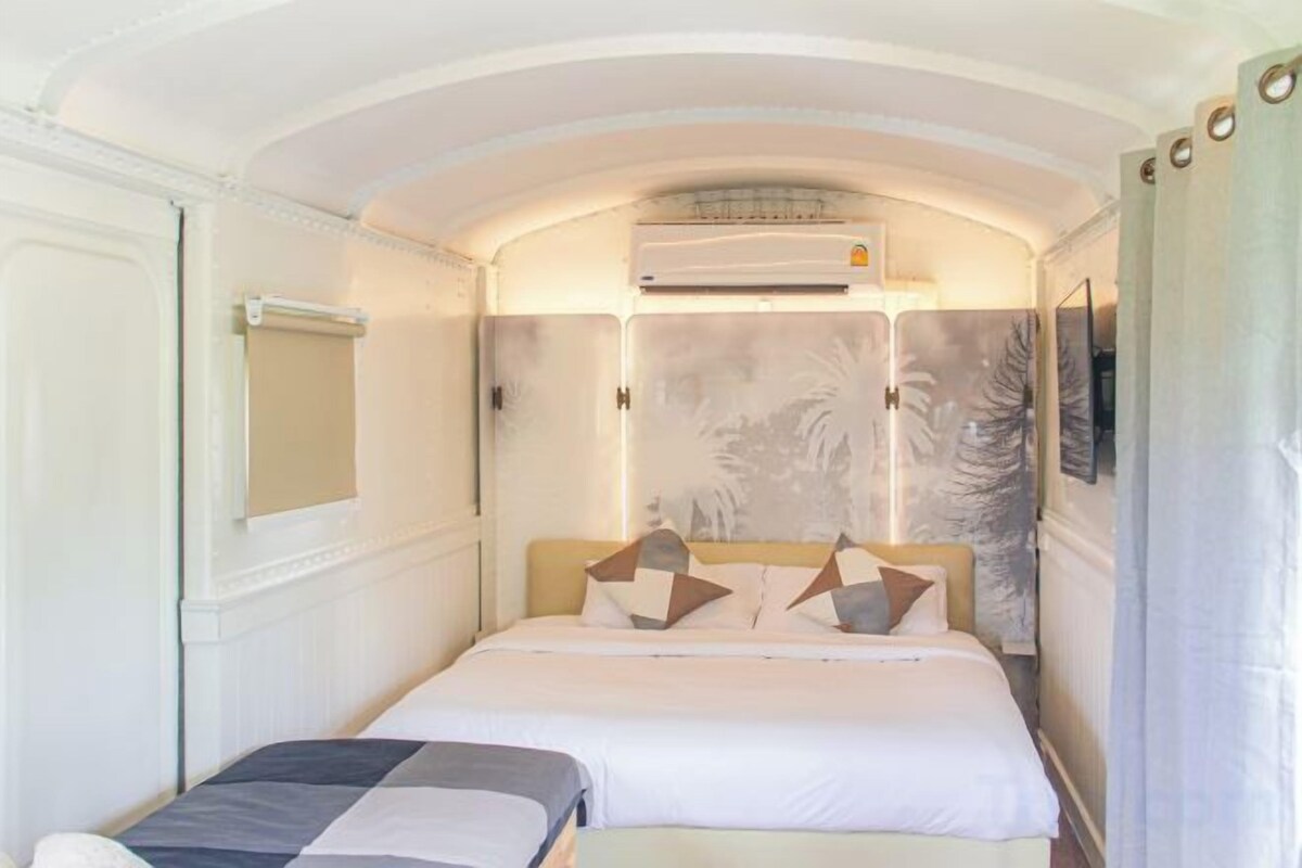 Een hotelkamer met een bed, een slaapbank of extra bed, een airconditioning en een raam met gordijn.