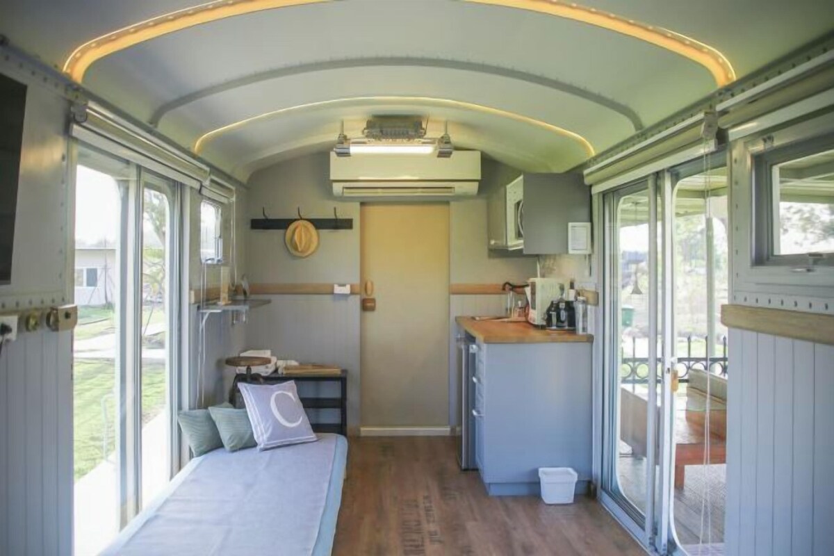 Un interior compacto con cama, kitchenette y ventanas amplias.