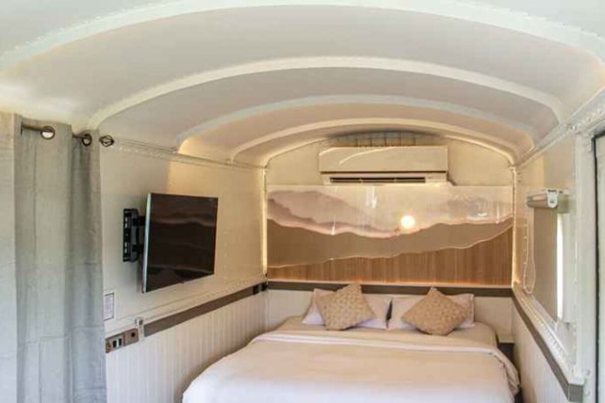 Une chambre à coucher comprenant un lit, un téléviseur à écran plat et un climatiseur fixé au mur.