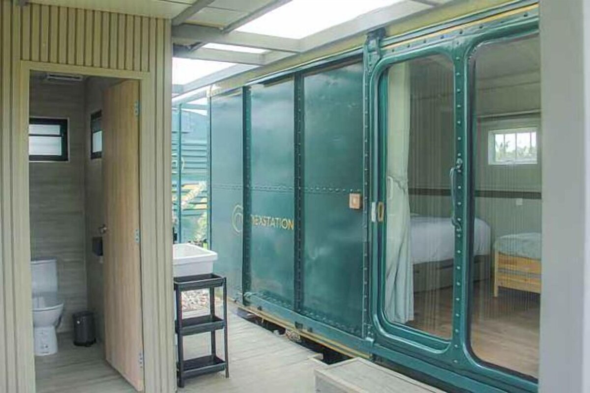 A train car converted into a sleeping car with a small bathroom and a bed.