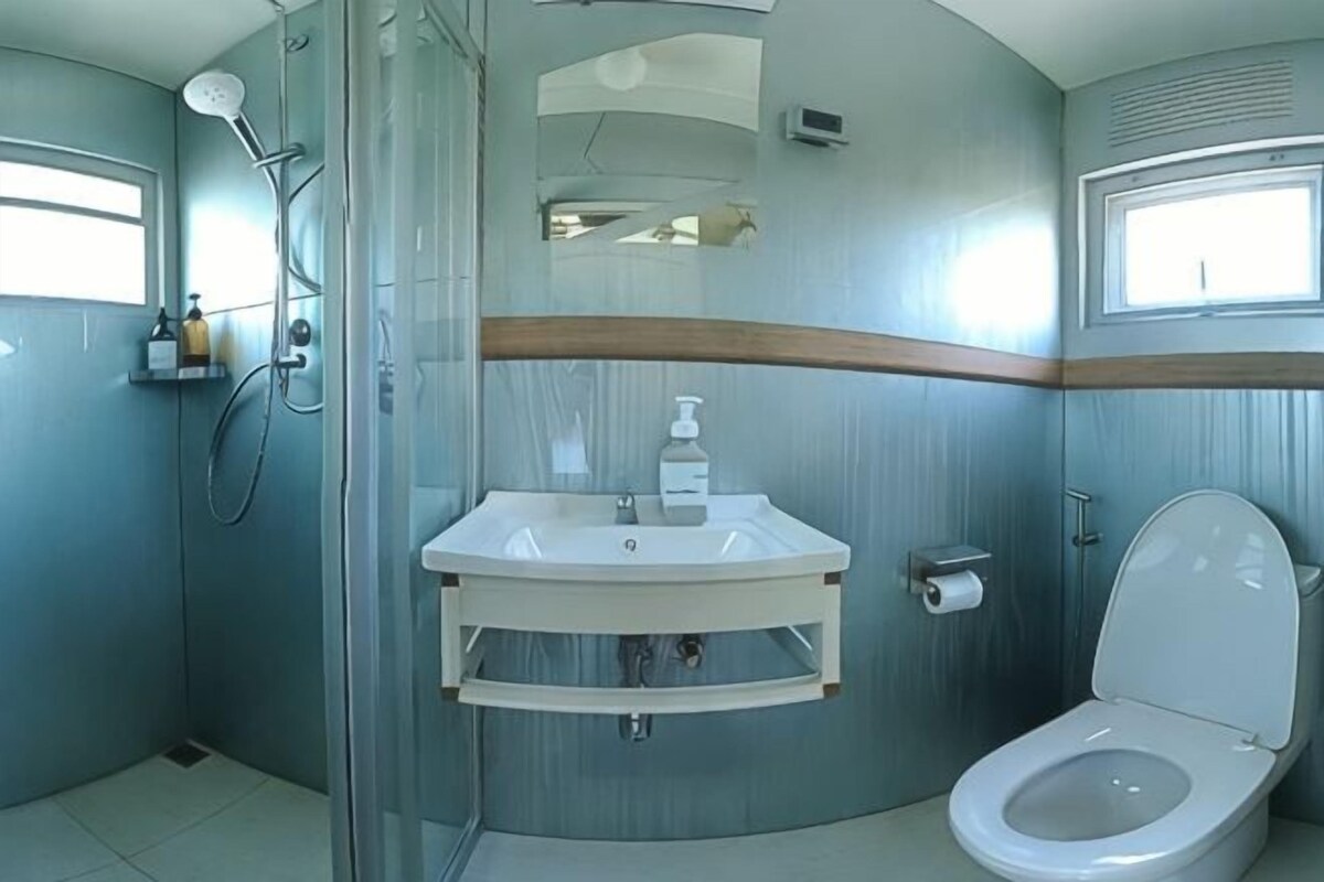 A bathroom with a glass shower enclosure, a sink with a mirror, and a toilet.