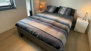 Una camera da letto moderna con un letto grande, una lampada a sospensione, un comodino e un quadro appeso al muro.