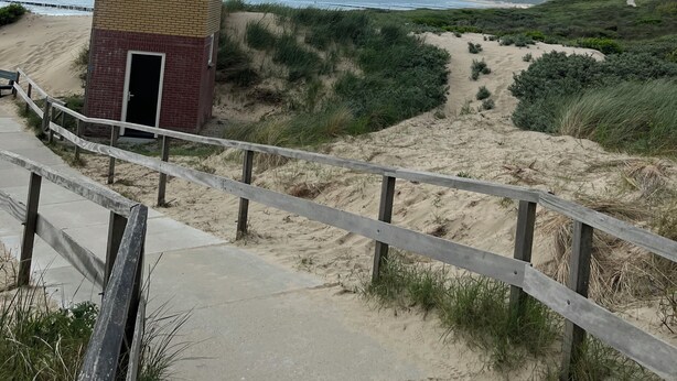 Una torre costiera con un sentiero sabbioso che vi conduce, affacciata su una spiaggia e l'oceano.