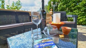 A table with a wine bottle, glasses, a book titled 'Mallorca', and a bowl of fruit. - Villa in Manacor with Pool and Tennis Court (Manacor)
