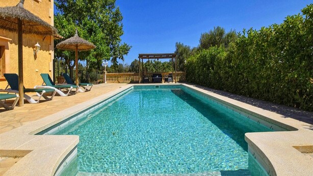 A rectangular swimming pool with clear blue water, surrounded by lounge chairs and a pergola structure. - Villa in Manacor with Pool and Tennis Court (Manacor)