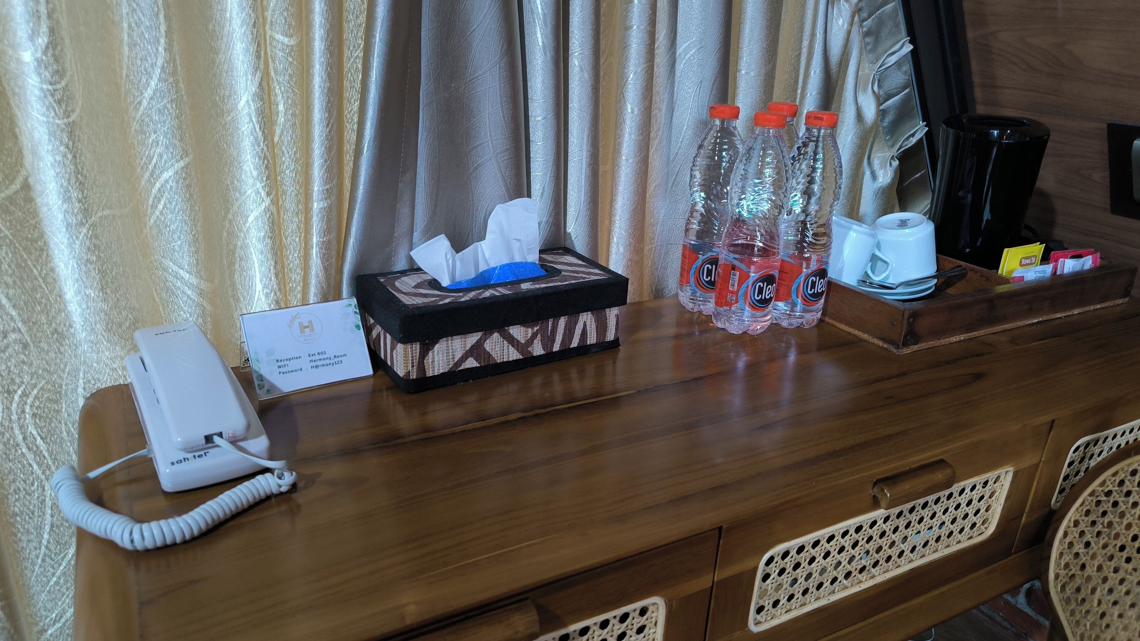 Mostrador de recepción de hotel con teléfono, caja de pañuelos, agua embotellada y cafetera.