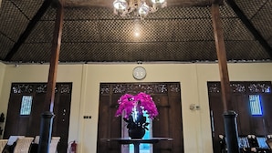 Un vaste hall doté d’un plafond haut, d’un décor orné et d’un lustre central.