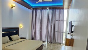 Une chambre à coucher avec un lit, un ventilateur de plafond, une télévision et une table en bois.
