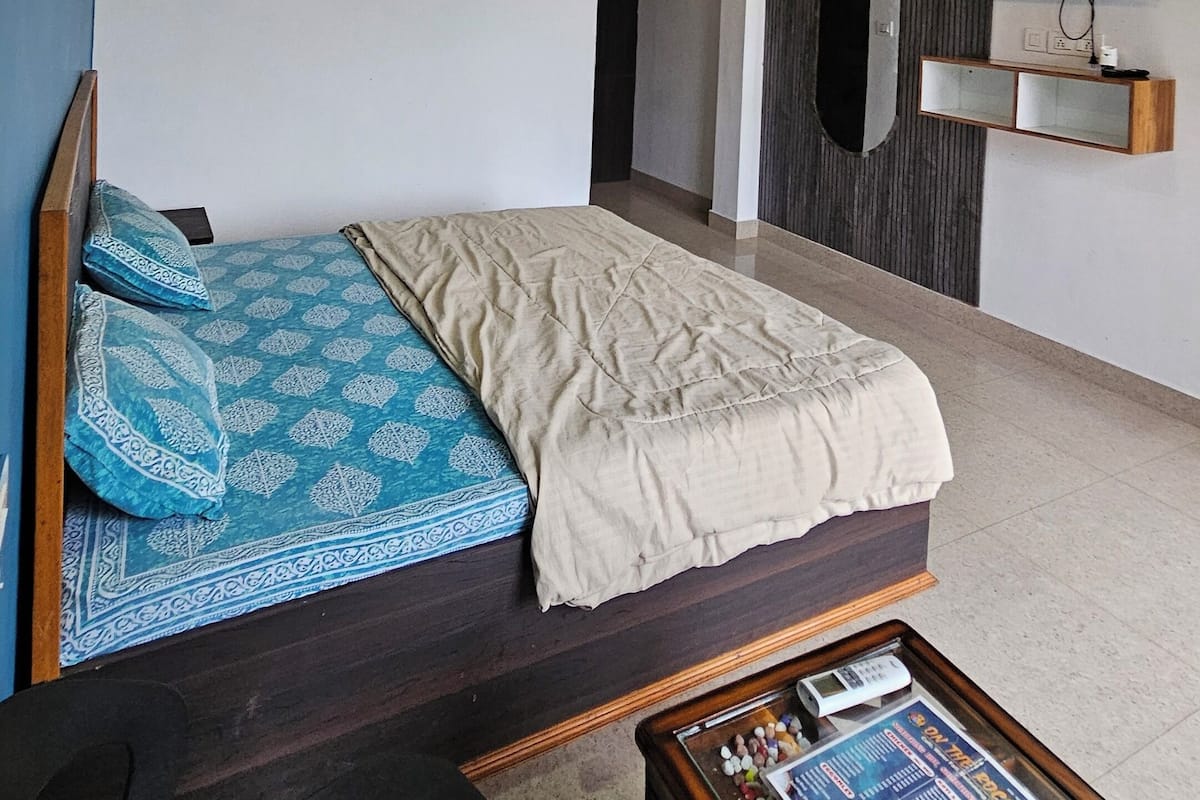 Une chambre moderne avec un lit, une télévision et une petite table sur laquelle sont posés des magazines.