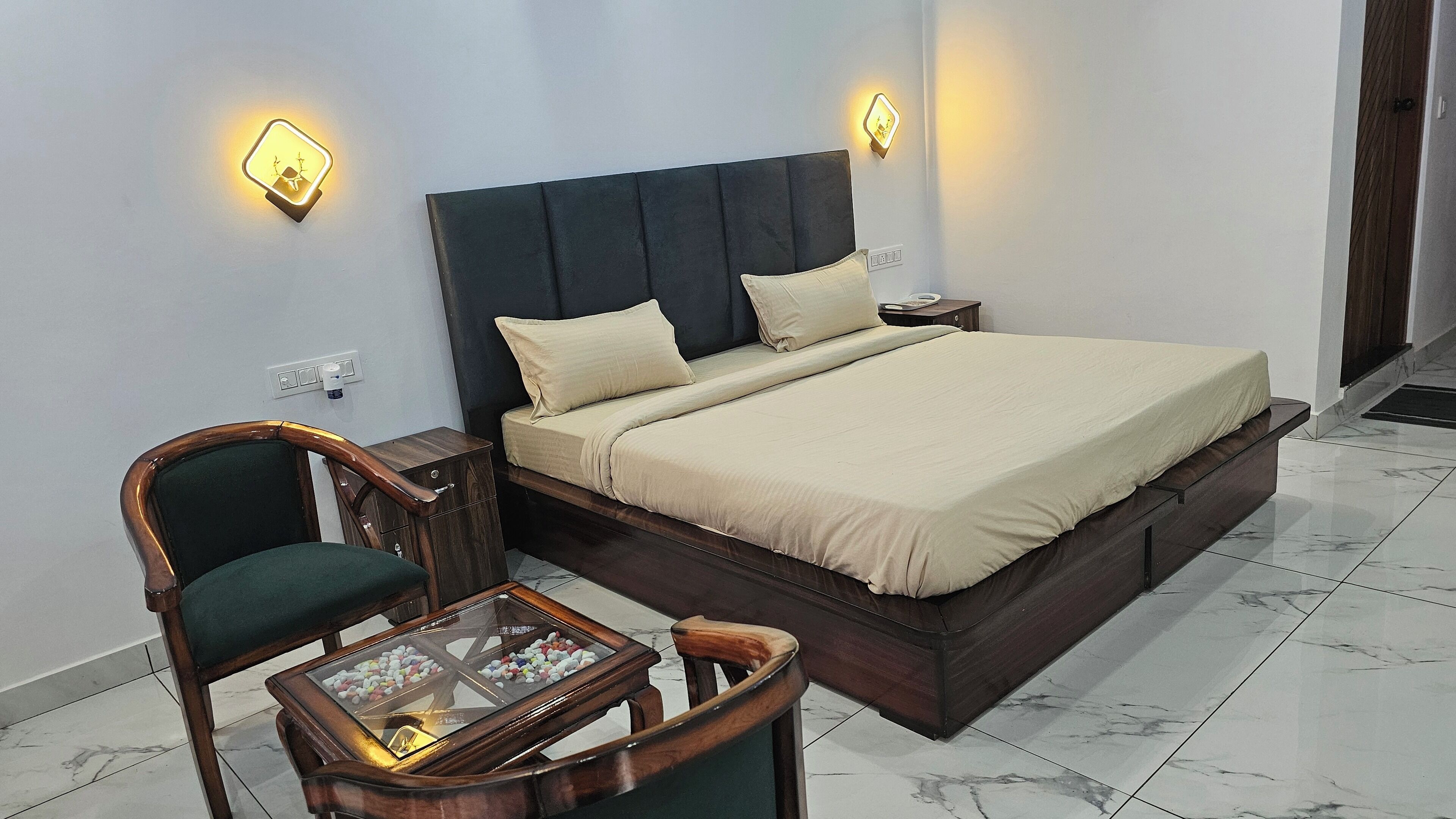 A neatly arranged bedroom with a bed, bedside tables, a chair, and a glass-top coffee table.