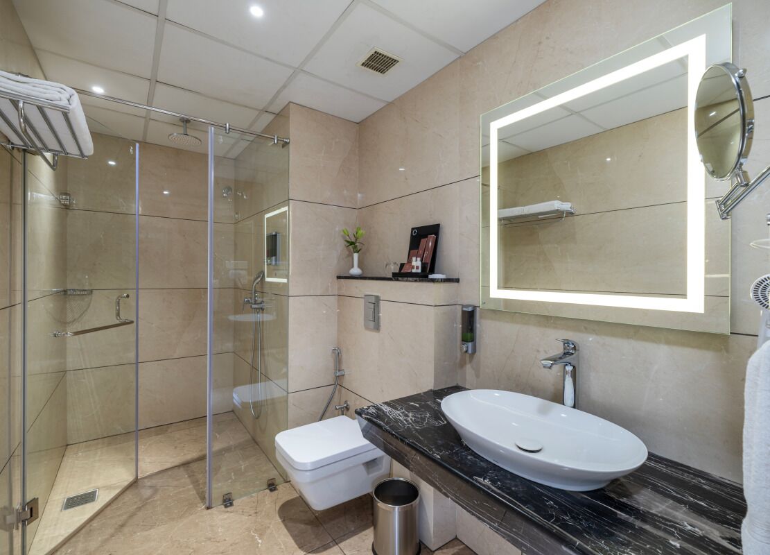 A modern bathroom with a glass-enclosed shower, a white sink, and a large mirror.