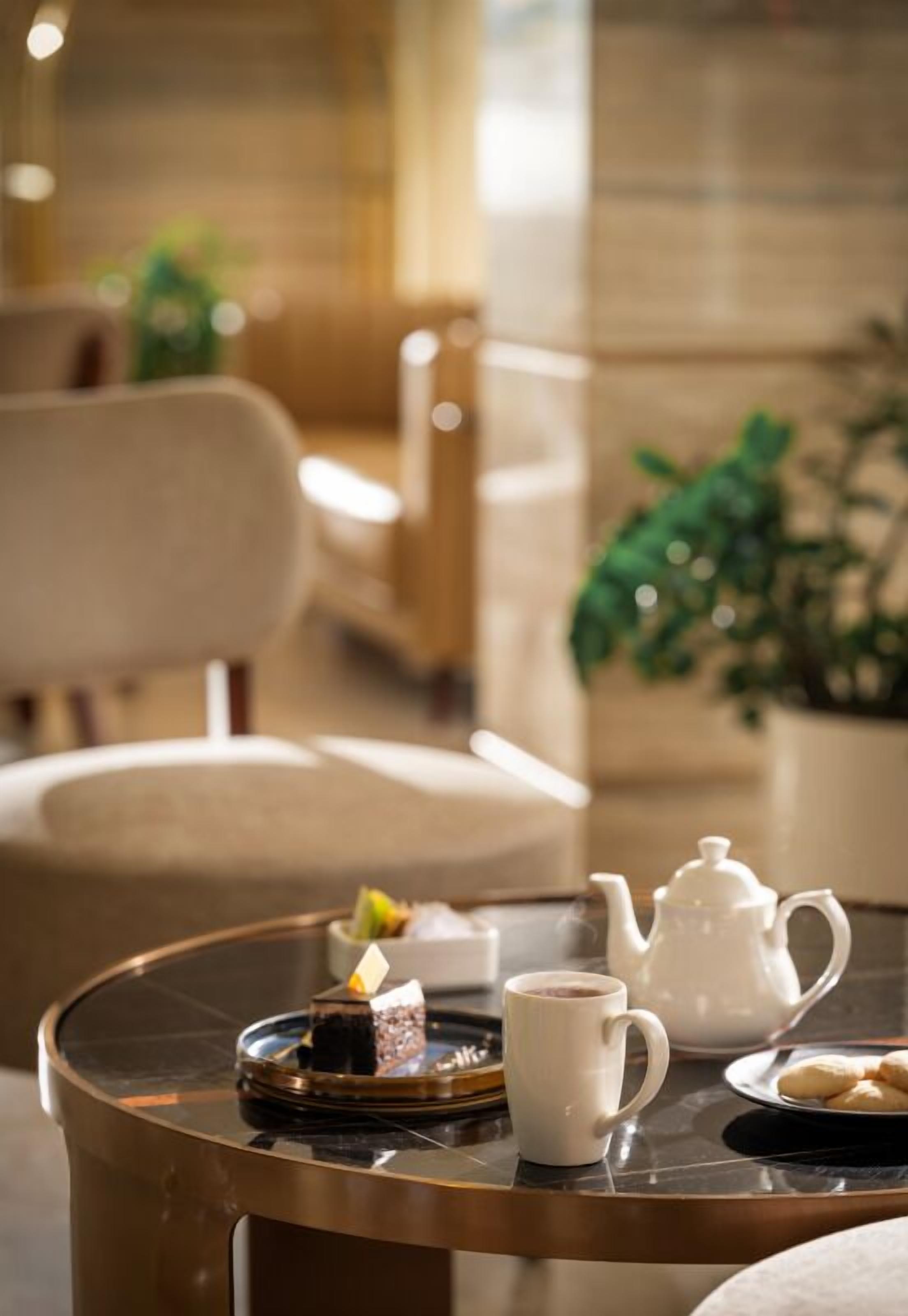 A round table with a teapot, a cup, a plate with cookies, and a small decorative item.