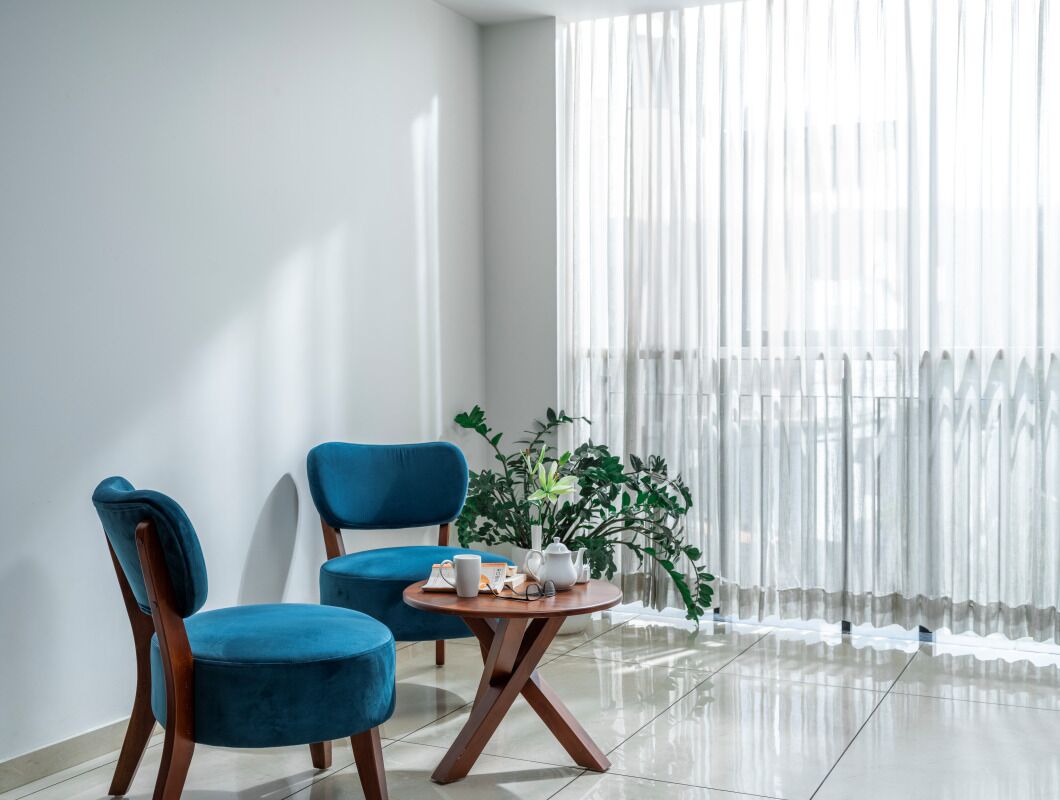 A modern room with two blue chairs, a small round table, and a potted plant.