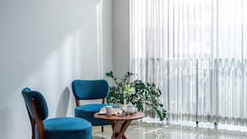 A modern room with two blue chairs, a small round table, and a potted plant.