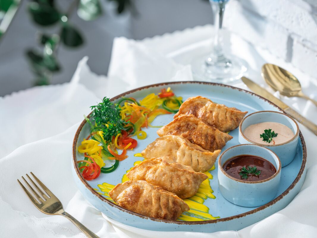 A plate of food with dumplings, a side salad, and two dipping sauces.