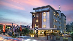 A modern hotel with a prominent sign for 'Osh Hotel' and 'Wescaide' on the ground floor. - Nexstay Oshin Wayanad (Vythiri)
