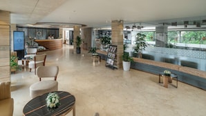 A spacious lobby with a reception desk, seating area, and potted plants. - Nexstay Oshin Wayanad (Vythiri)