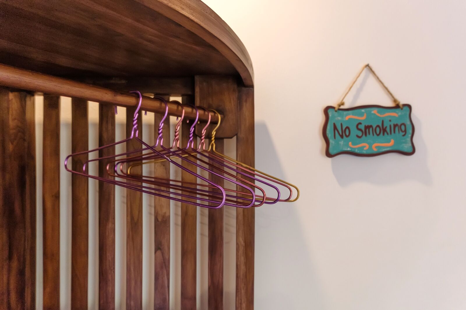 Une porte en bois avec un porte-manteau en métal et un panneau « Il est interdit de fumer » sur le mur.