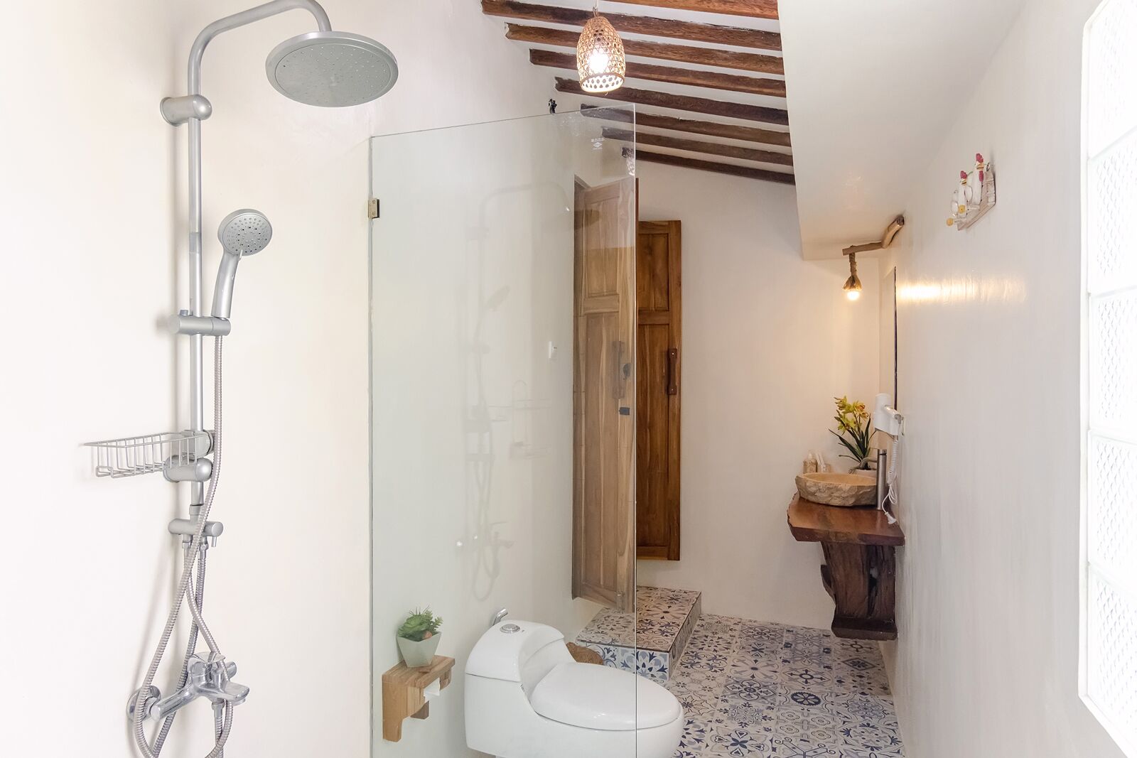 Een moderne badkamer met een douchecabine van glas, een wit toilet en een houten wastafelmeubel met een wastafel.