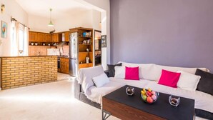 A modern living room with a sofa, coffee table, and a kitchen area in the background. - The Olive Grove Two-Bedroom Apartment by Konnect, Dassia  (Corfu)