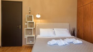 A neatly arranged hotel room with a bed, a wardrobe, a bedside table with a lamp, and a shelf with decorative items. - The Olive Grove Two-Bedroom Apartment by Konnect, Dassia  (Corfu)