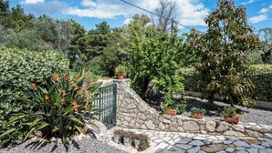 A garden with a stone wall, potted plants, and a metal gate. - The Olive Grove Two-Bedroom Apartment by Konnect, Dassia  (Corfu)