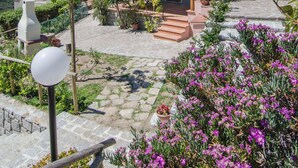 A pink villa with a covered patio, stone steps, and a view of the sea. - Casa Gelso, Vista Mare e Relax Nella Natura (Patresi)