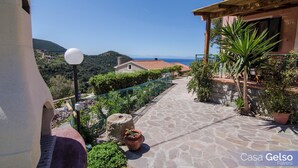 A stone-paved pathway leading to a house with a view of the sea. - Casa Gelso, Vista Mare e Relax Nella Natura (Patresi)