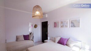 A hotel room with two beds, a hanging light fixture, and wall art. - Casa Gelso, Vista Mare e Relax Nella Natura (Patresi)