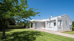 Une maison moderne à deux étages, dotée d’un patio couvert, d’un chemin en pierre et d’une pelouse bien entretenue.