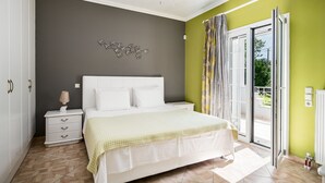 Une chambre à coucher comprenant un lit, des tables de chevet, une lampe, un élément décoratif mural et une porte-fenêtre coulissante donnant sur l’extérieur.