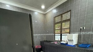 A modern kitchen with grey tiled walls, a black refrigerator, and a window with a grid pattern. - FWA guest house  (Marang)