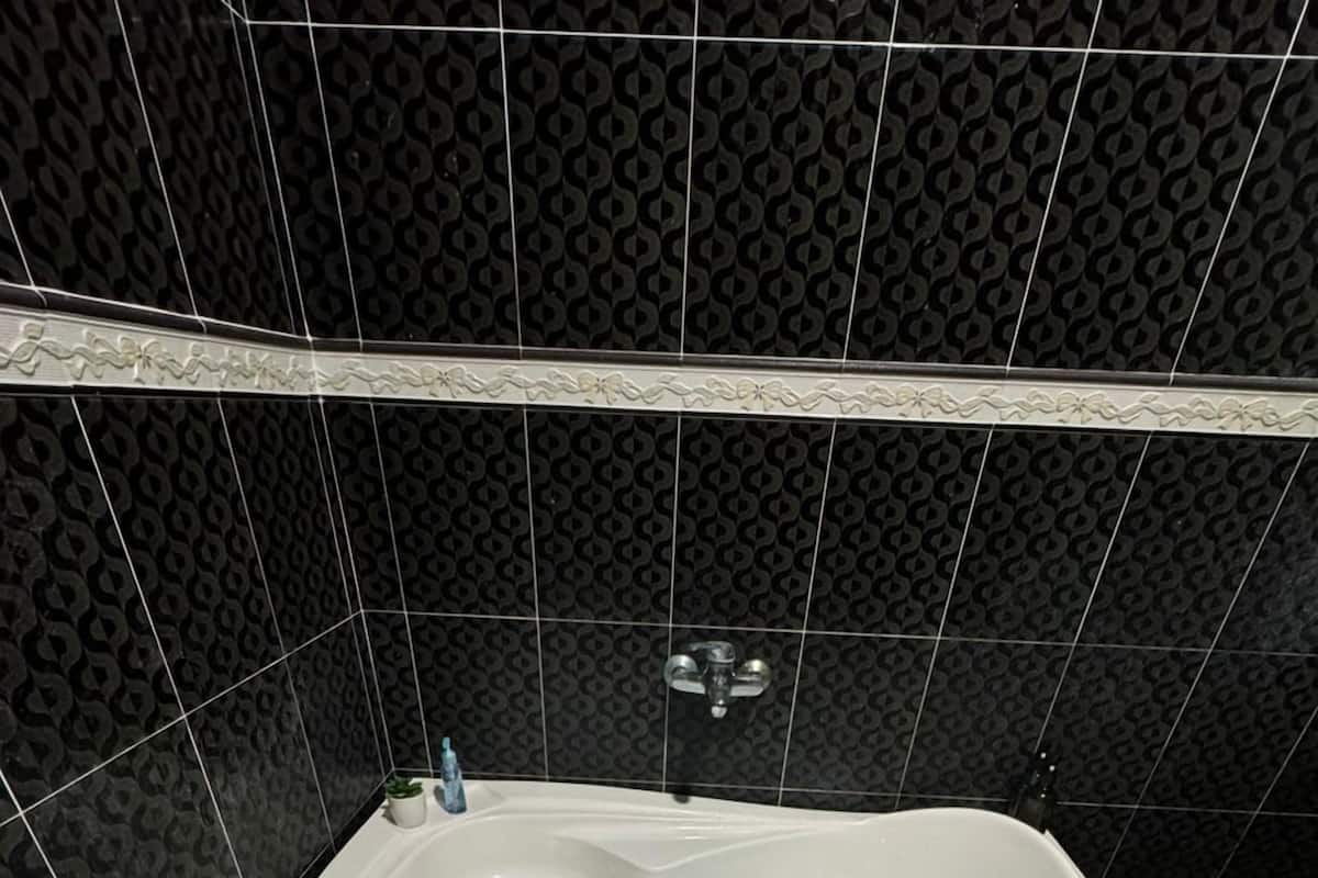 A bathtub with rose petals in water, a faucet, and a showerhead.