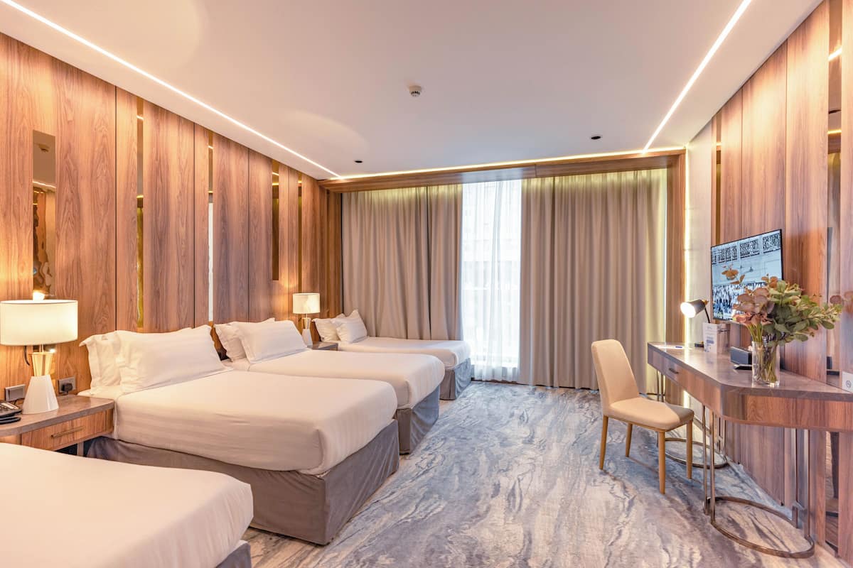Una habitación de hotel con tres camas, un escritorio y una silla.